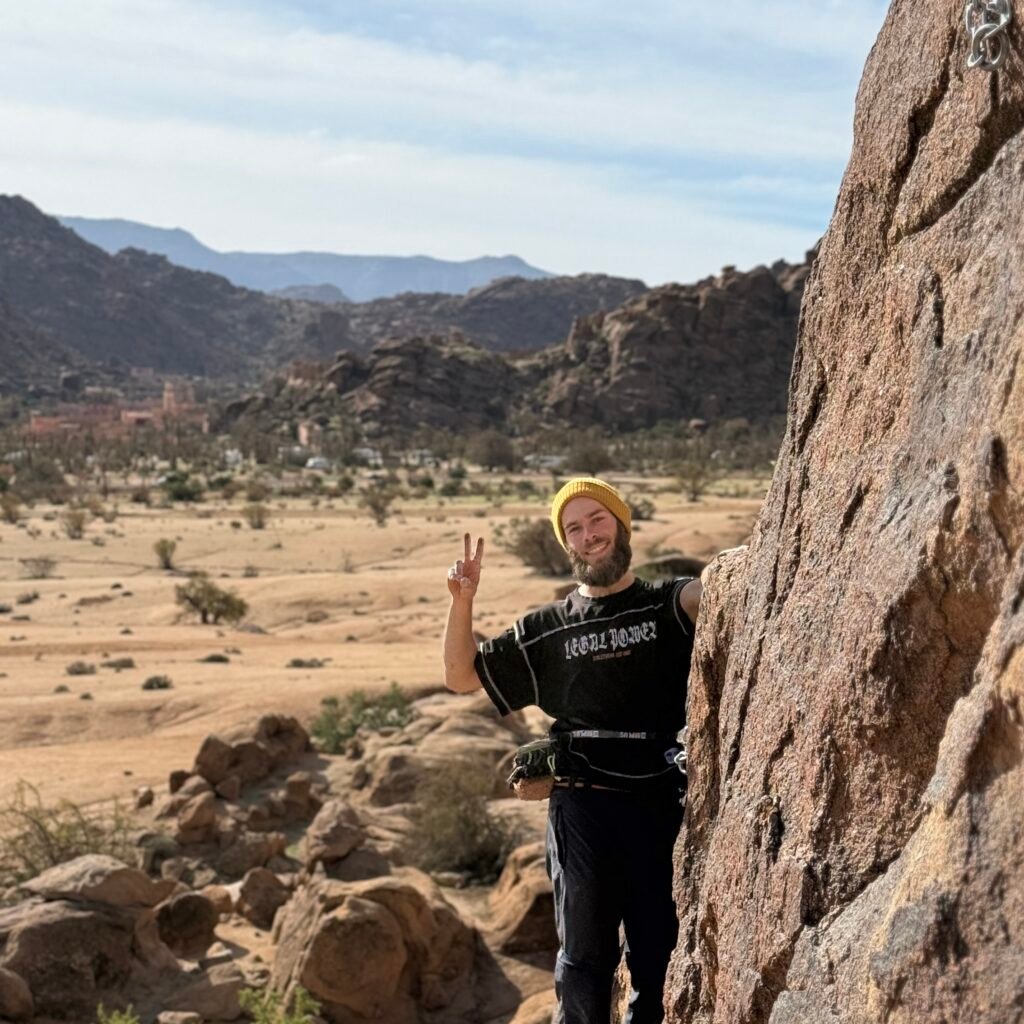Climber scaling a steep granite overhang using safety ropes in Tafraoute, Morocco