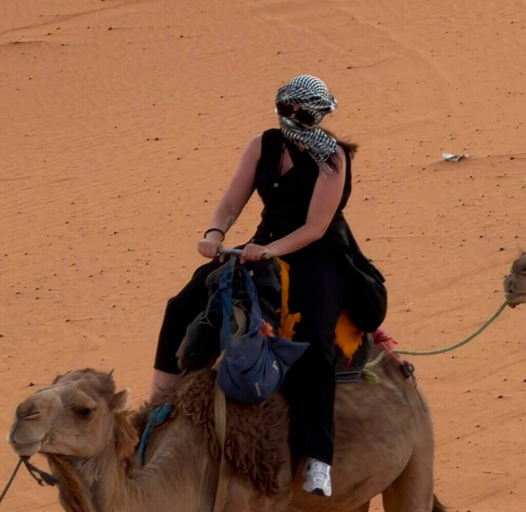 Solo traveler riding a camel across the desert dunes on a Sahara trekking tour