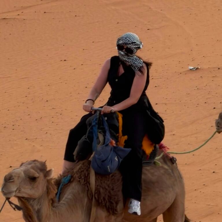Solo traveler riding a camel across the desert dunes on a Sahara trekking tour