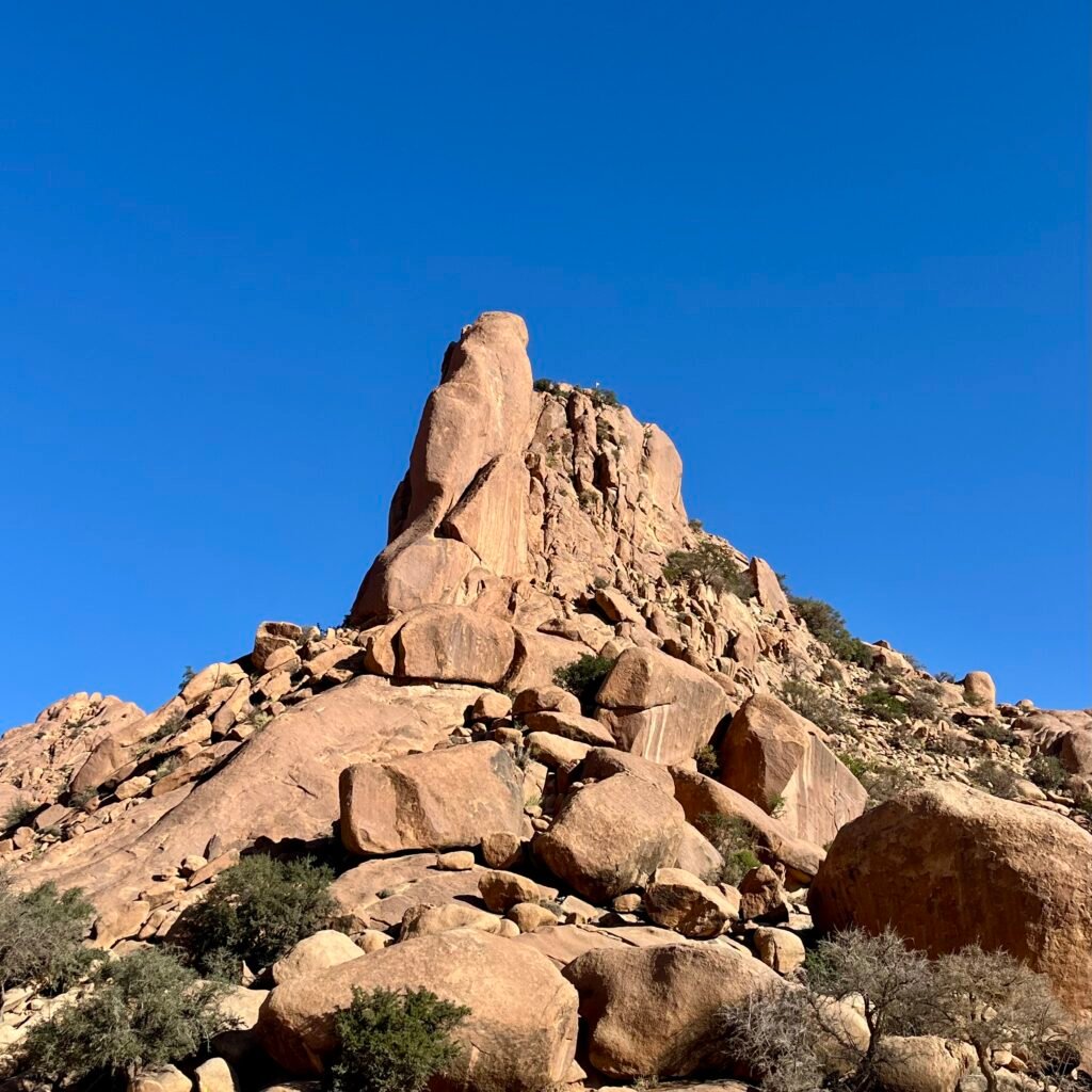 Massive granite rock formation rising under a clear blue sky in Tafraoute, Morocco