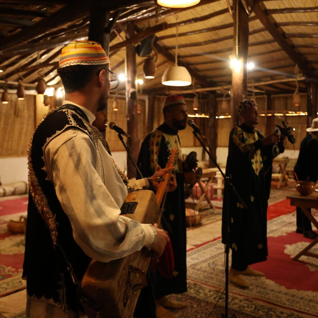 Musician playing a traditional stringed instrument alongside band members performing in a rustic venue