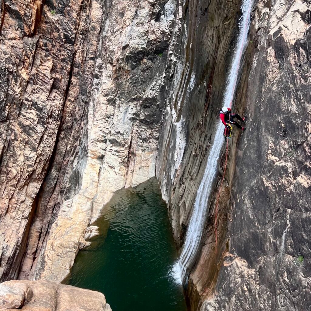 Canyoning tour participant abseiling down a massive rock face in a mountain gorge in Morocco