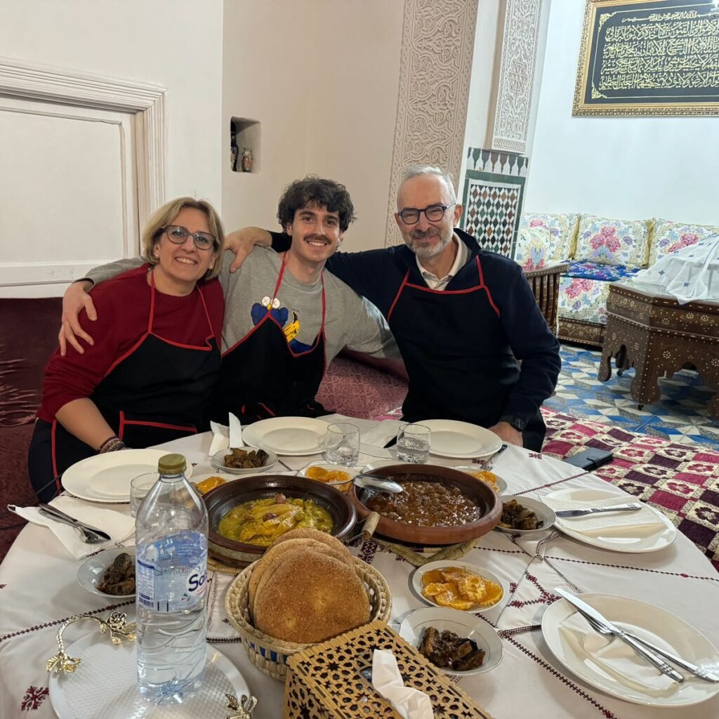 Family members in aprons gathered around a table with a spread of traditional Moroccan dishes