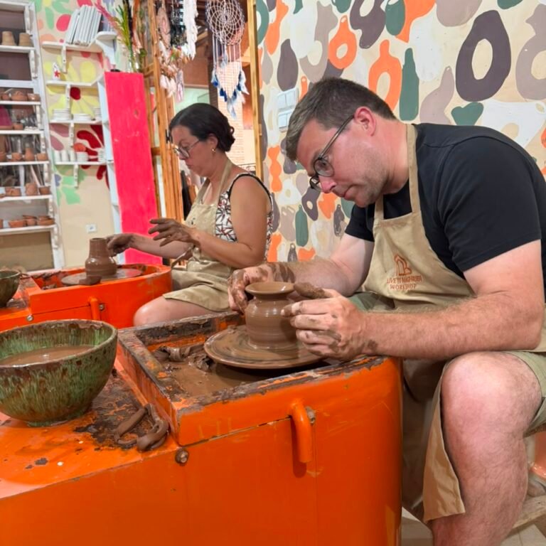 Travelers wearing aprons crafting clay pots on pottery wheels in a workshop