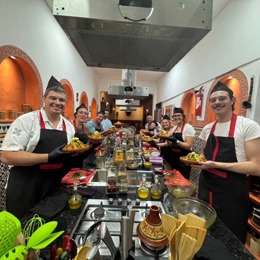 Group of smiling participants posing with freshly prepared vegetable tagines in a traditional kitchen