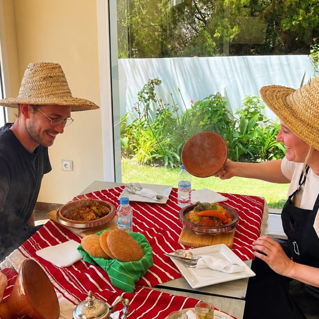 Travelers wearing straw hats enjoying a steaming traditional Moroccan tagine meal during a culinary experience