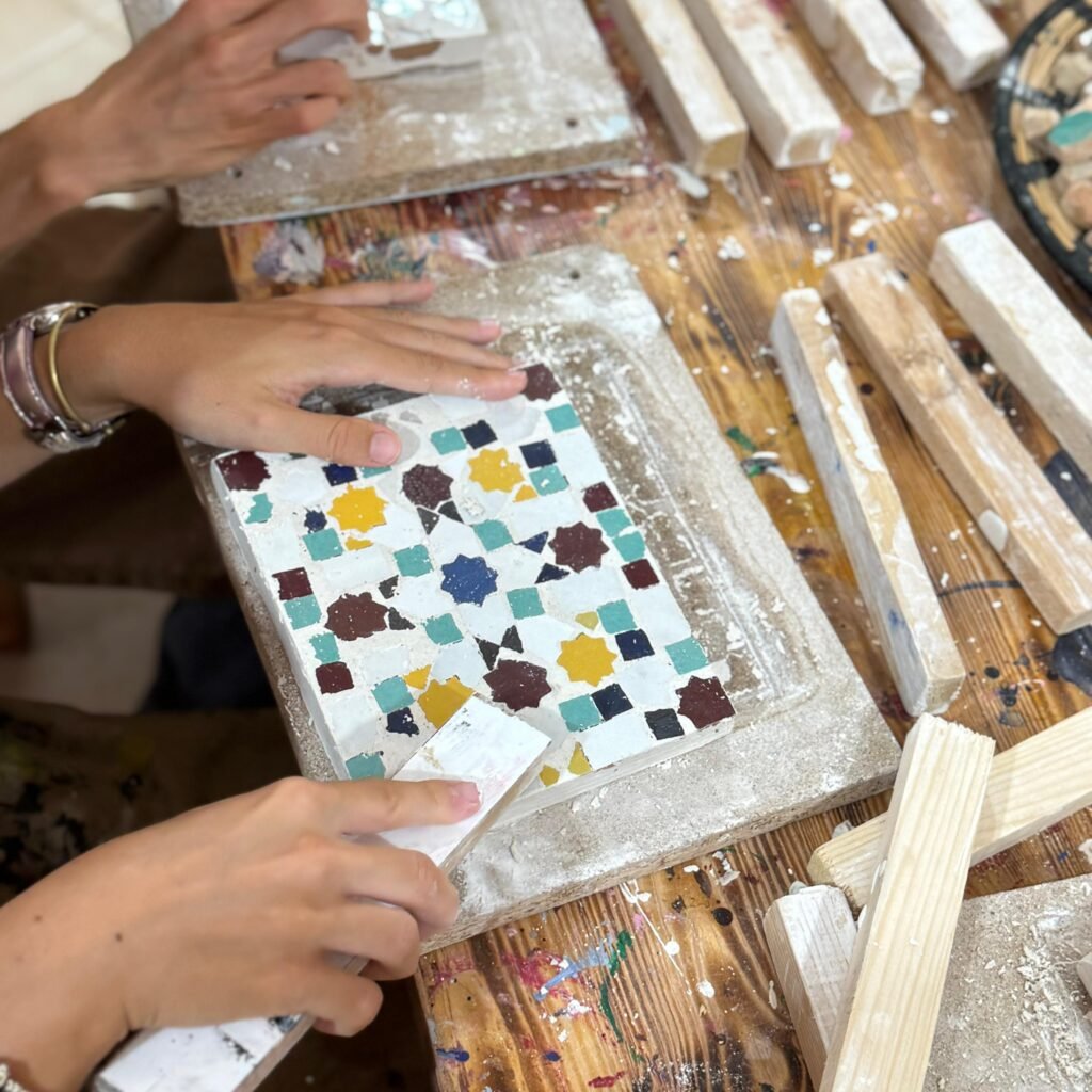 Workshop participant grouting and finishing a colorful zellij mosaic plaque