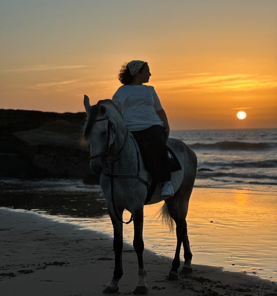 Silhouette of a woman riding a white horse on the beach during sunset in Morocco