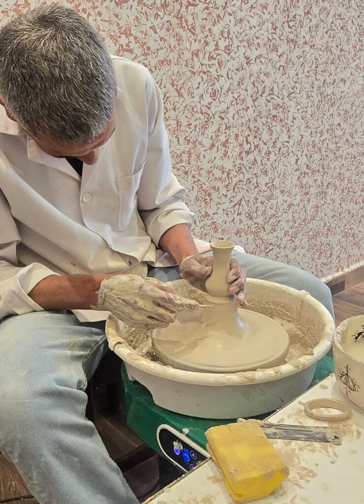 Expert potter shaping a delicate vase neck on a pottery wheel