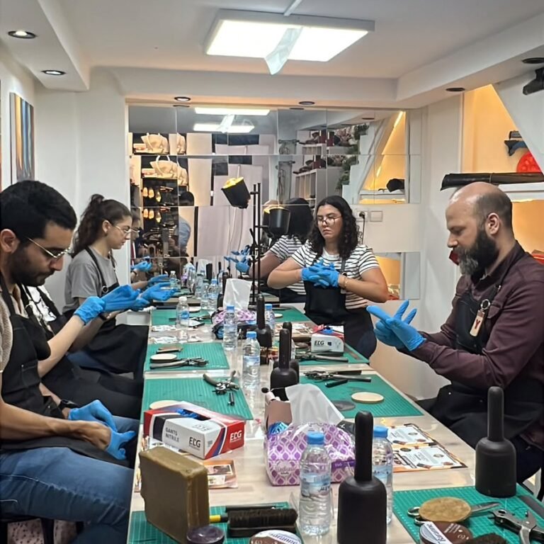 Workshop participants sitting along a work table putting on gloves to work with leather