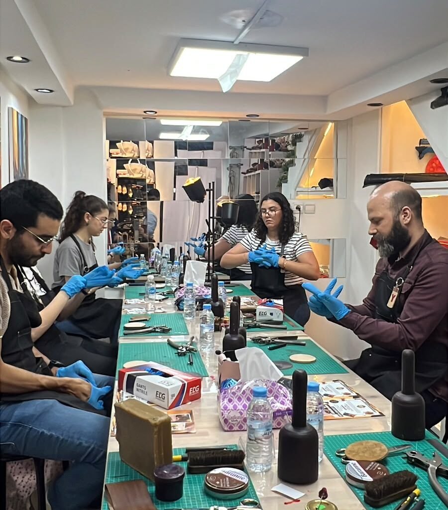 Workshop participants sitting along a work table putting on gloves to work with leather