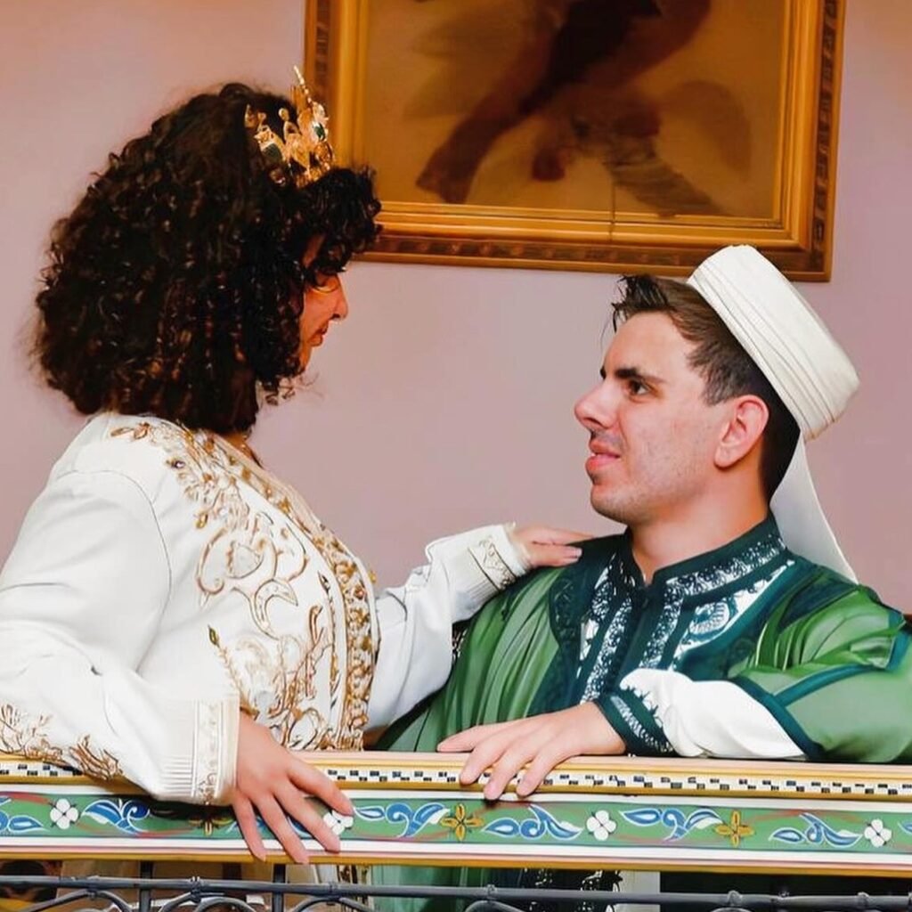 A couple leaning against an ornate decorative railing while wearing traditional Moroccan clothing