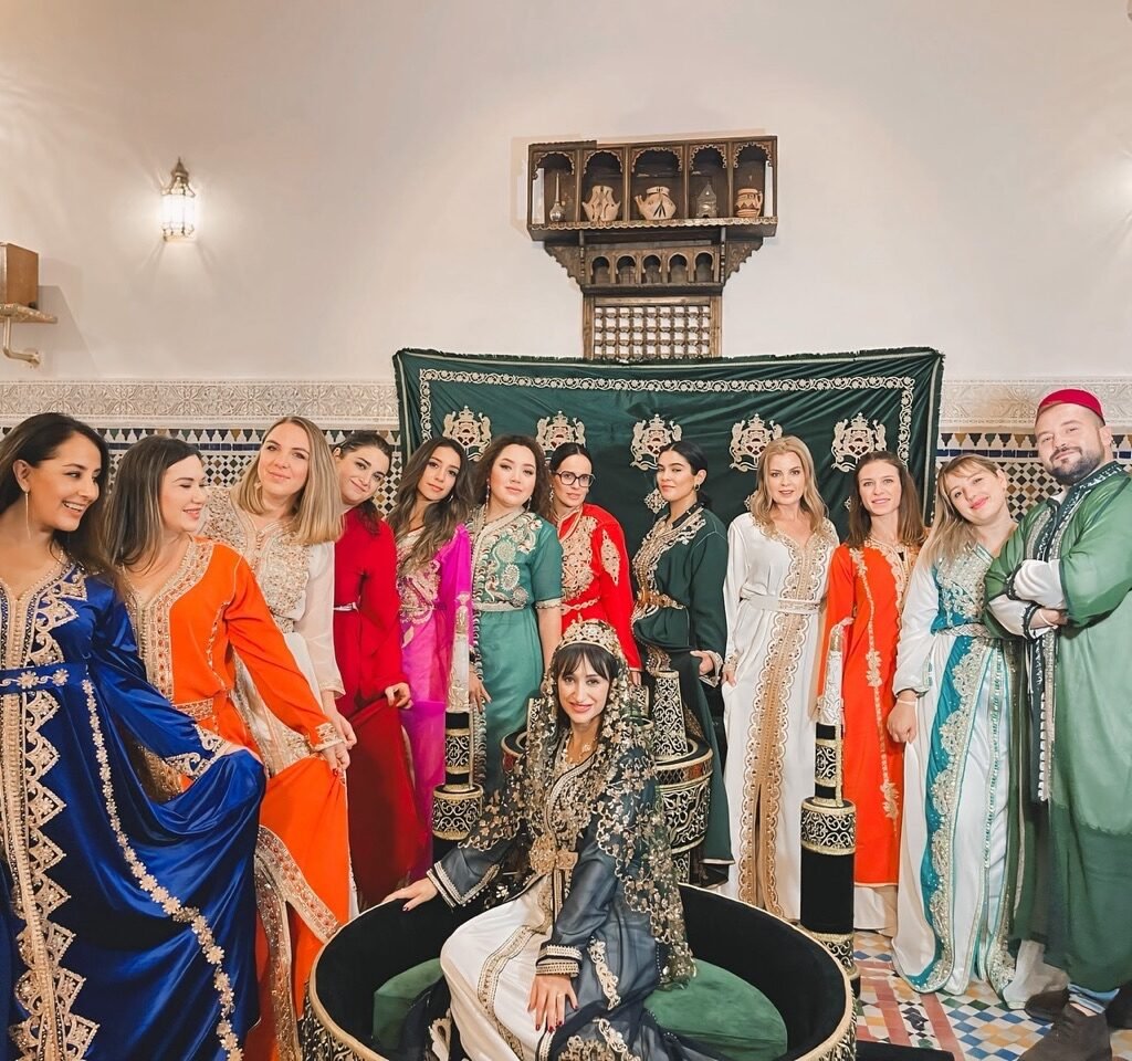 A group of travelers posing in traditional Moroccan kaftans of various vibrant colors during a cultural experience