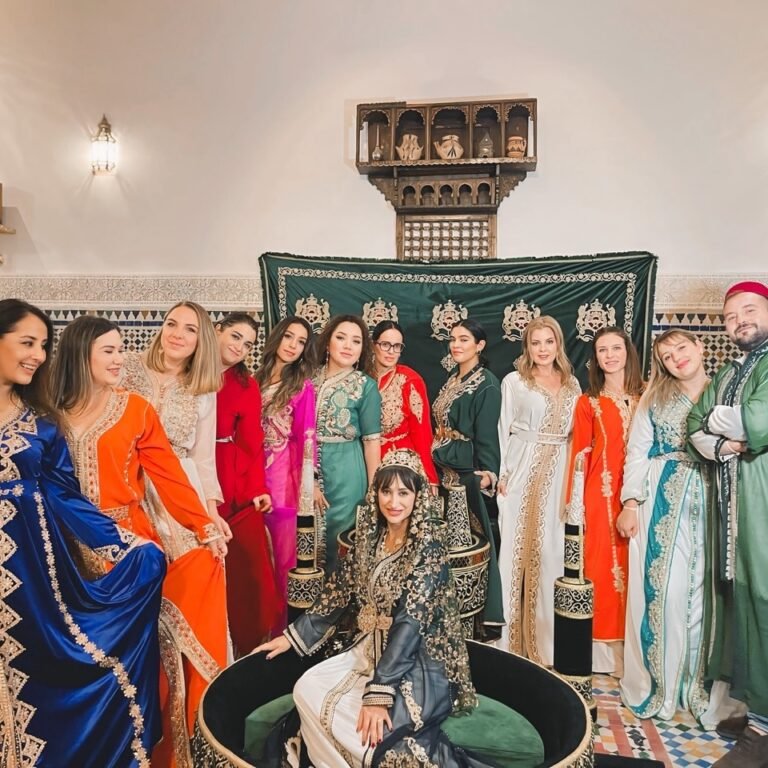 A group of travelers posing in traditional Moroccan kaftans of various vibrant colors during a cultural experience